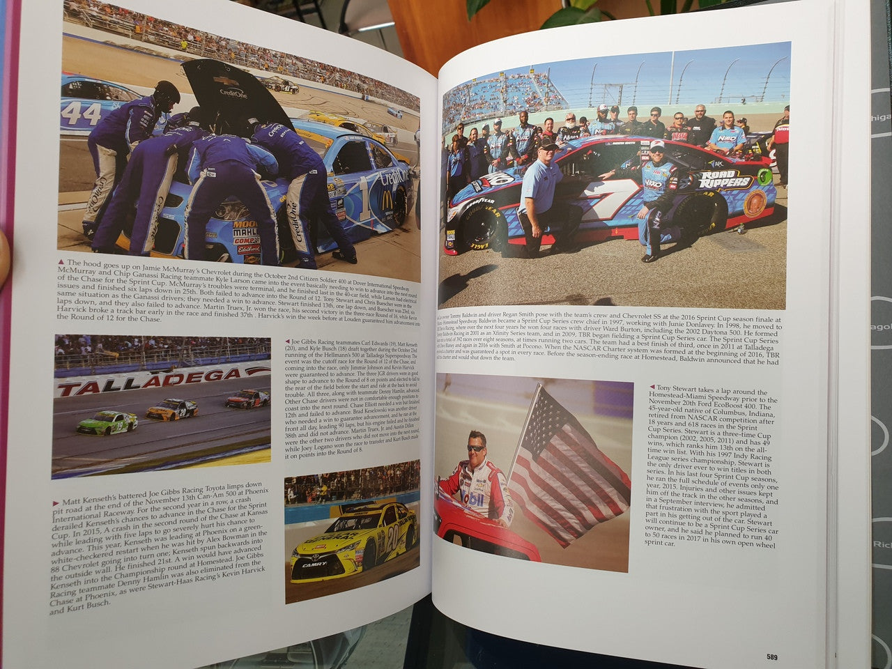 Hardcover NASCAR history book open to Talladega pages with packed track and American flag