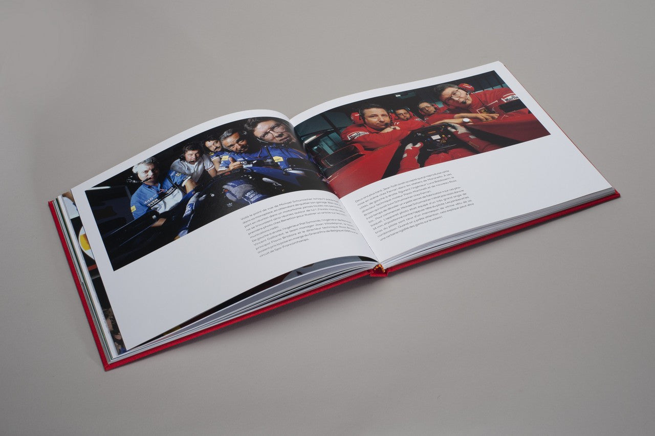 Open hardcover photo book with two-page spread of racing team photos