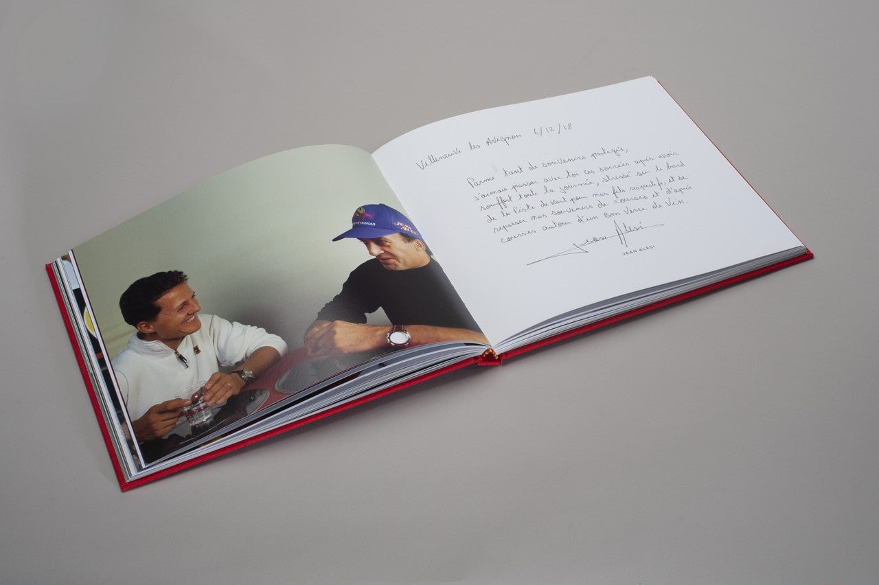 Open hardcover photo book with two men near cars and handwritten message page