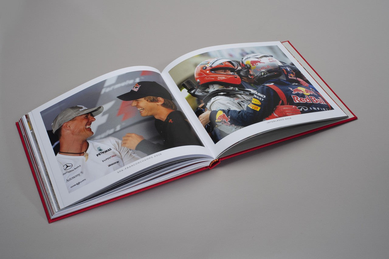 Open hardcover photo book with red race car action photos and crew close-ups