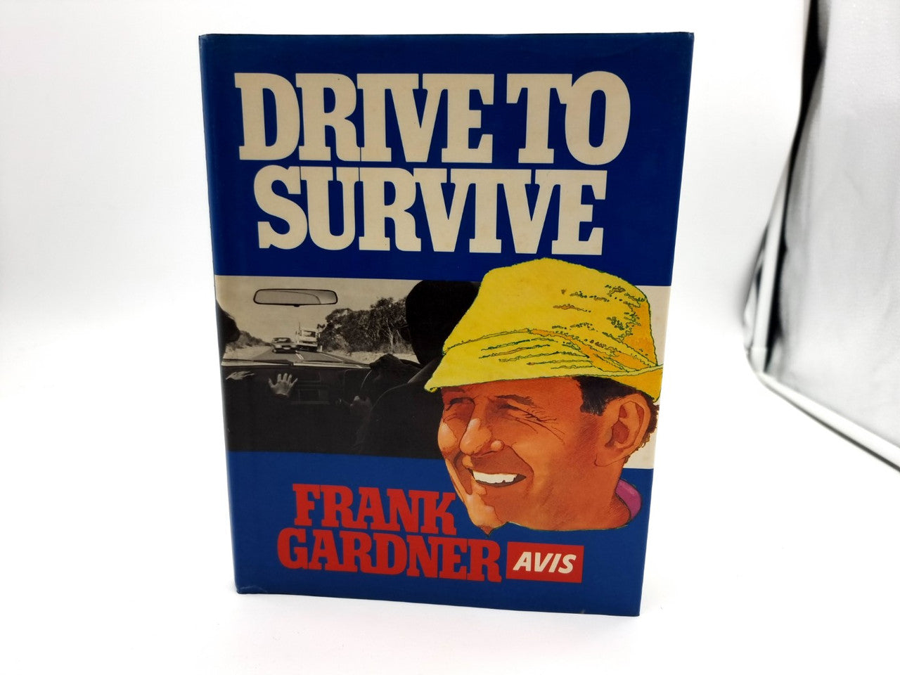Driving survival book standing with blue cover, yellow cap portrait, and Frank Gardner Avis