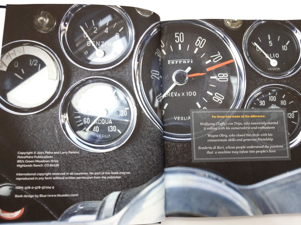 Hardcover book close-up of a vintage car dashboard with circular gauges and “ferrari” speedometer