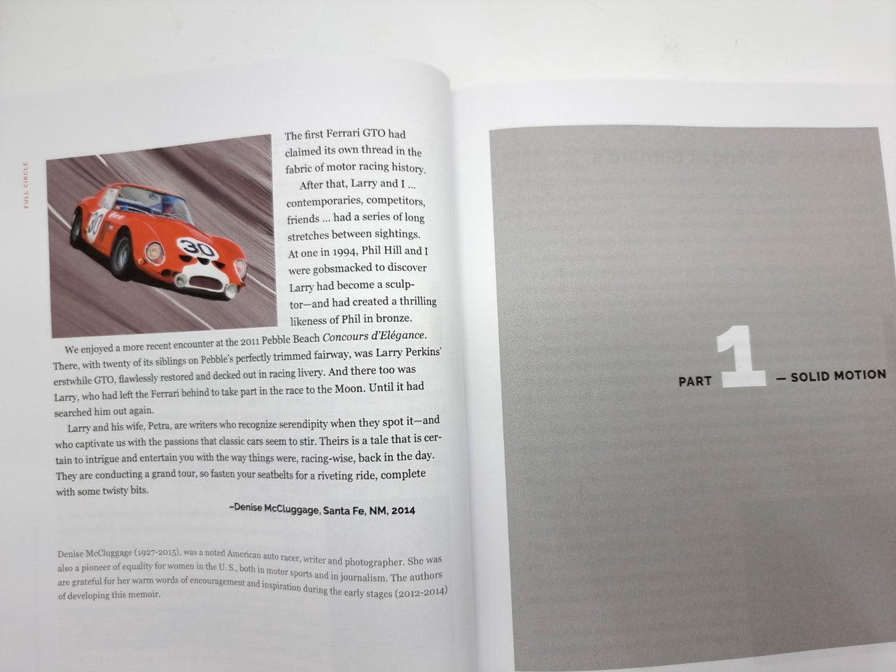 Hardcover book open to text page with small red race car photo and section labeled PART 1