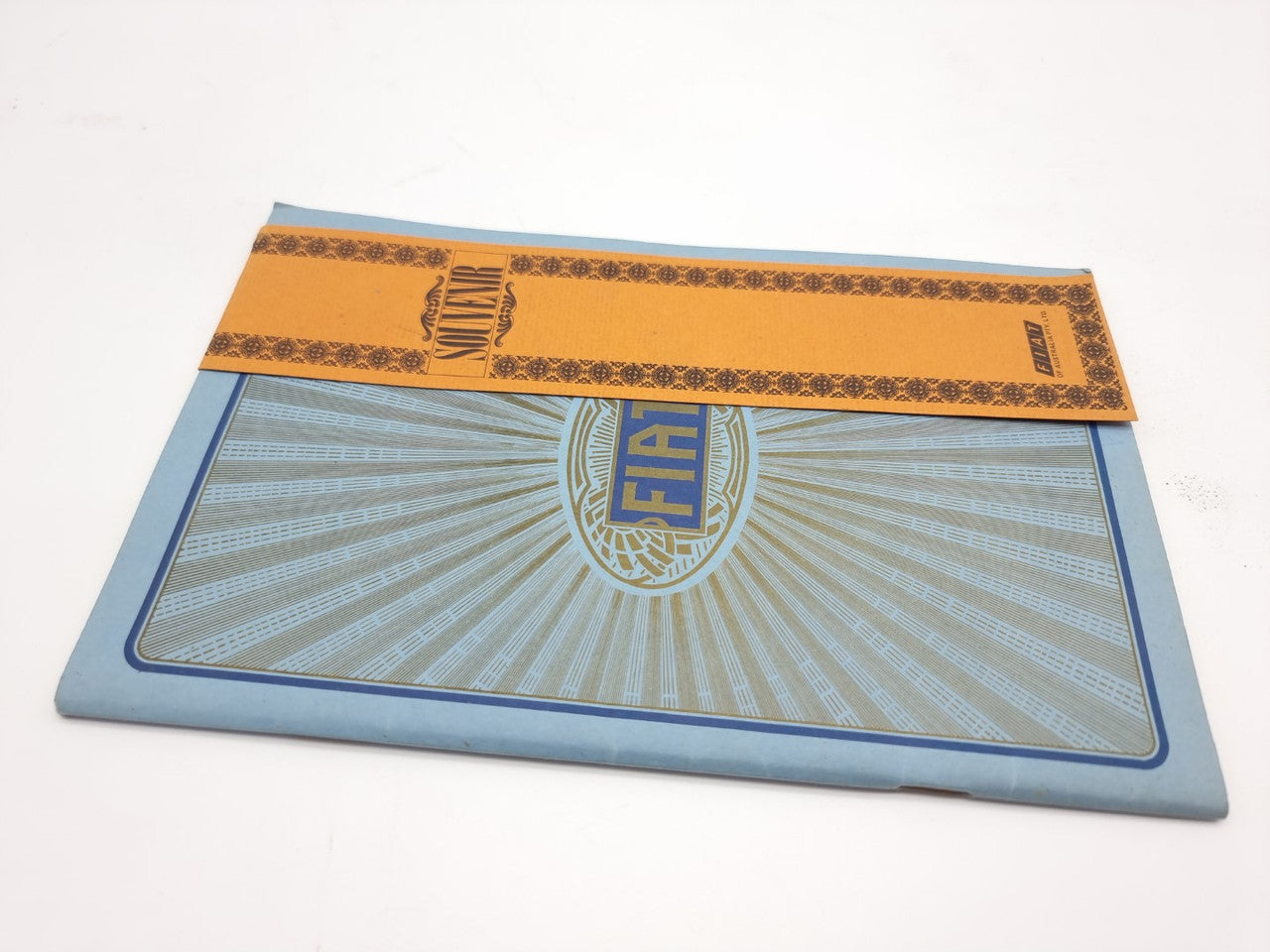 Fiat souvenir catalogue reprint with orange band and centered Fiat round logo on blue cover