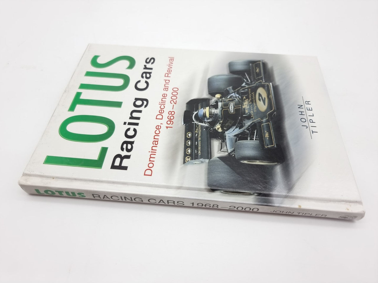 Auto racing book with green and white cover, black race car photo and author strip