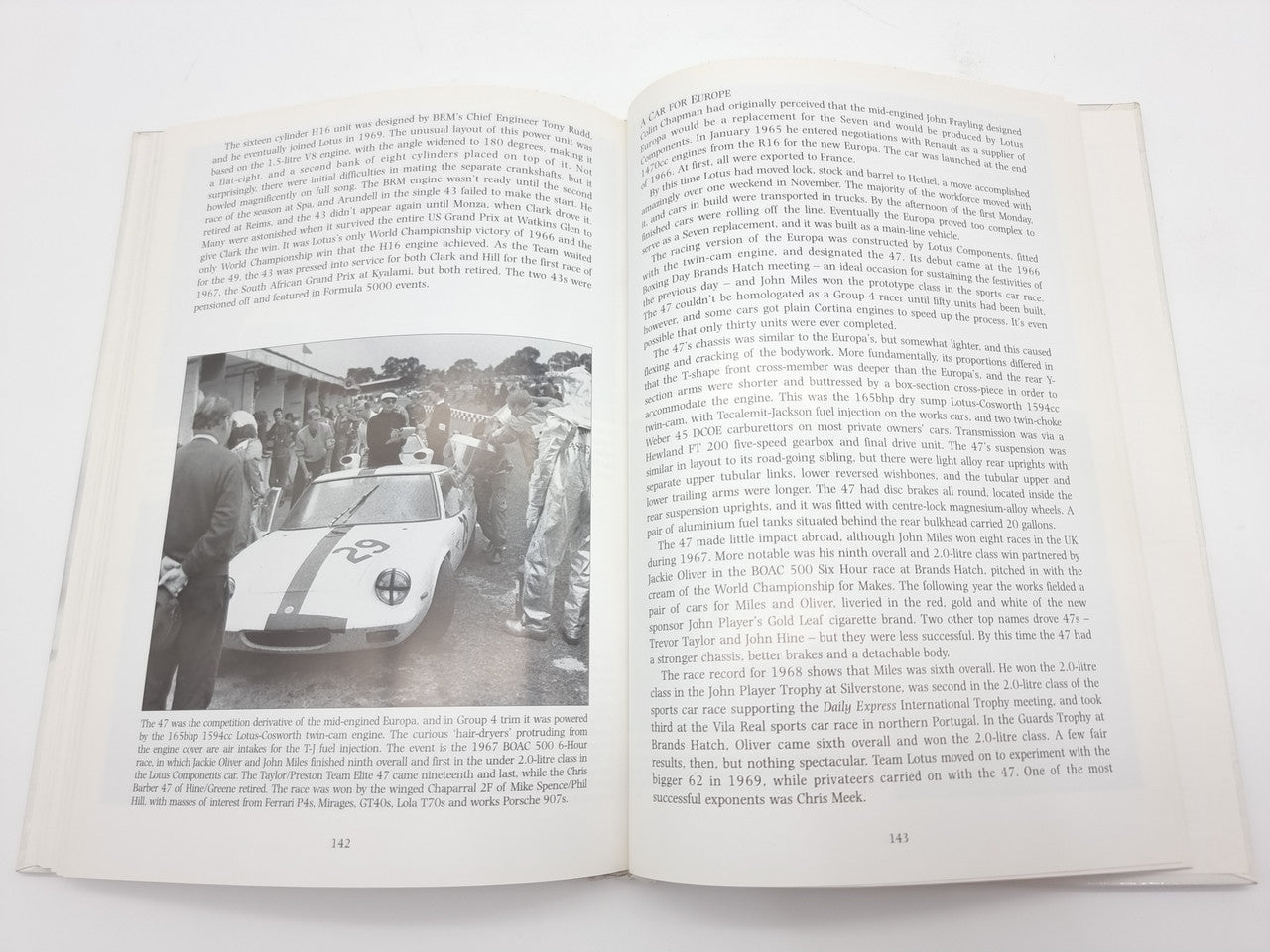 Open book with racing story text and front-view vintage car photograph