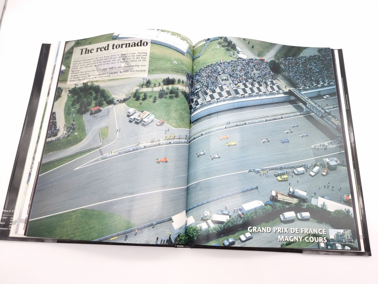 Open motorsport yearbook with aerial circuit view and grandstand crowd.