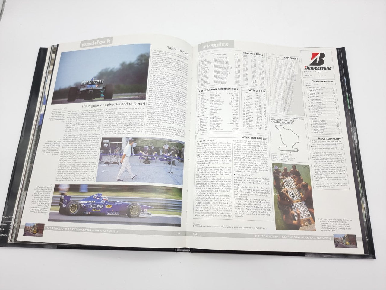Open motorsport yearbook with text and race photos on two-page spread.