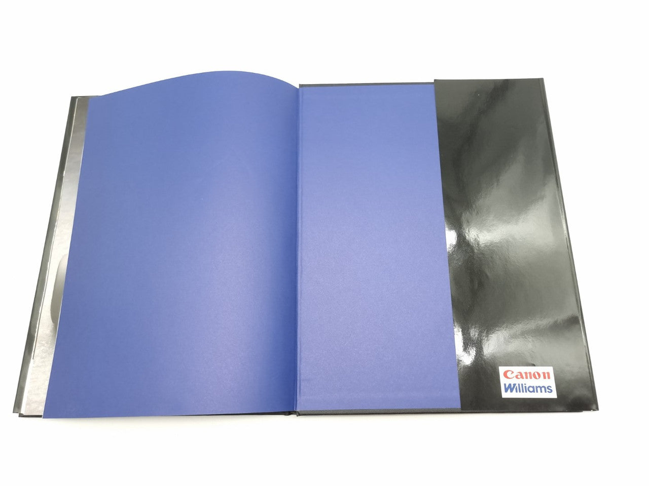 Hardcover photo book open to blue and gray pages with small logo at bottom right