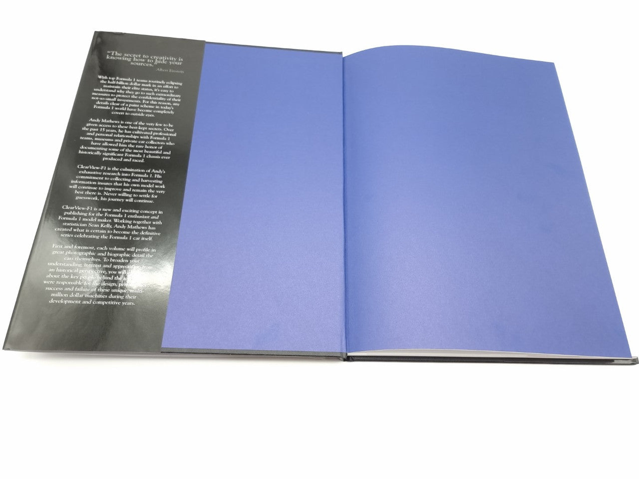 Open hardcover book with dark left page and solid blue right page