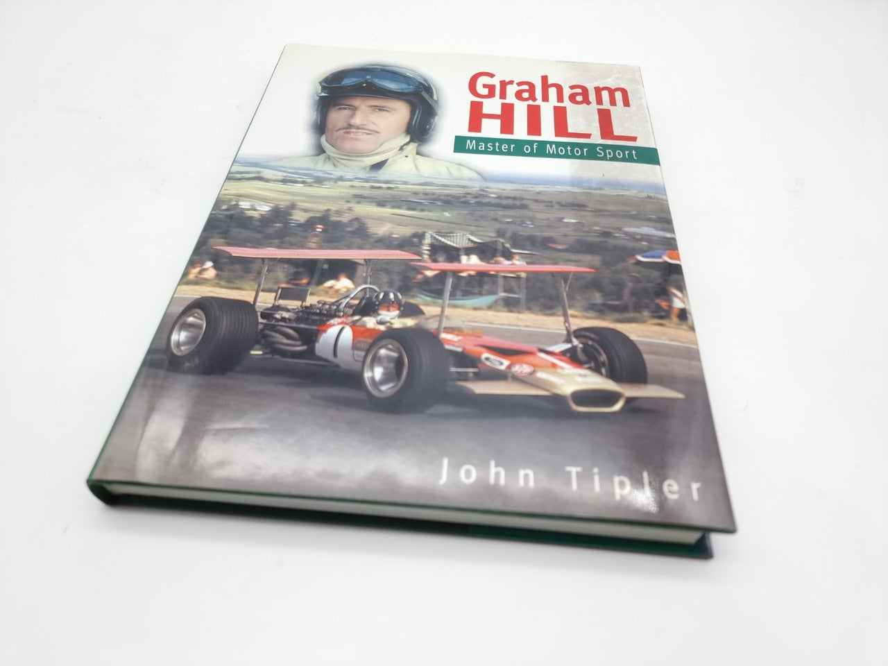Motorsport book cover with racer portrait, red car, and “Graham Hill” title