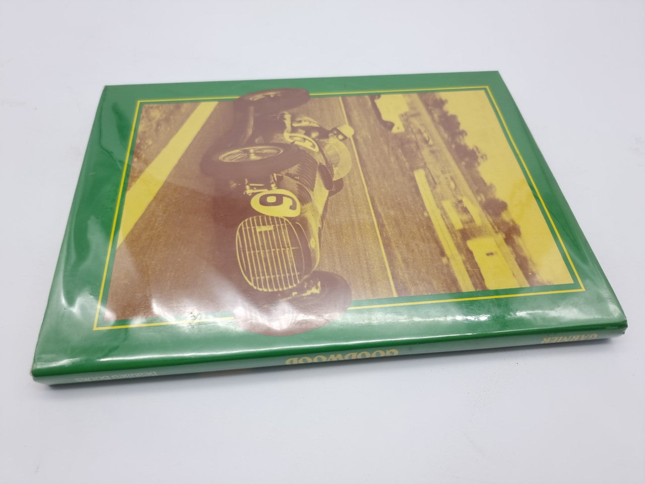 Hardcover book lying flat, green cover with racing car action photo