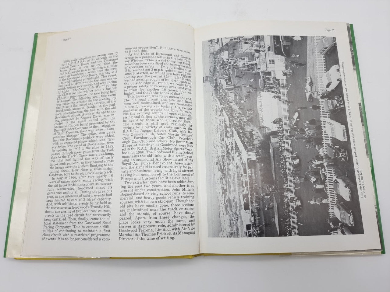 Open hardcover racing history book with text and a large black-and-white track aerial photo.