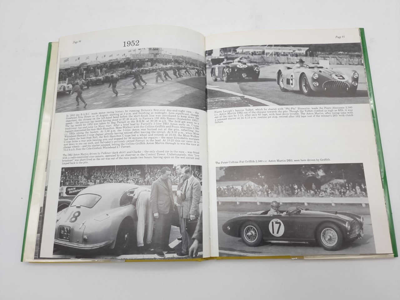 Open hardcover racing history book with large black-and-white car photos and a group scene.