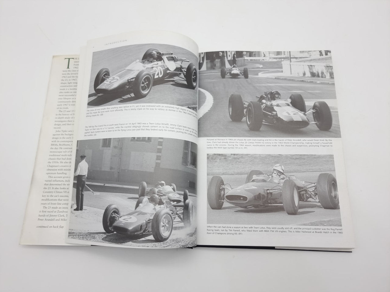 Open motorsport book with four grayscale race car photos and columns of text