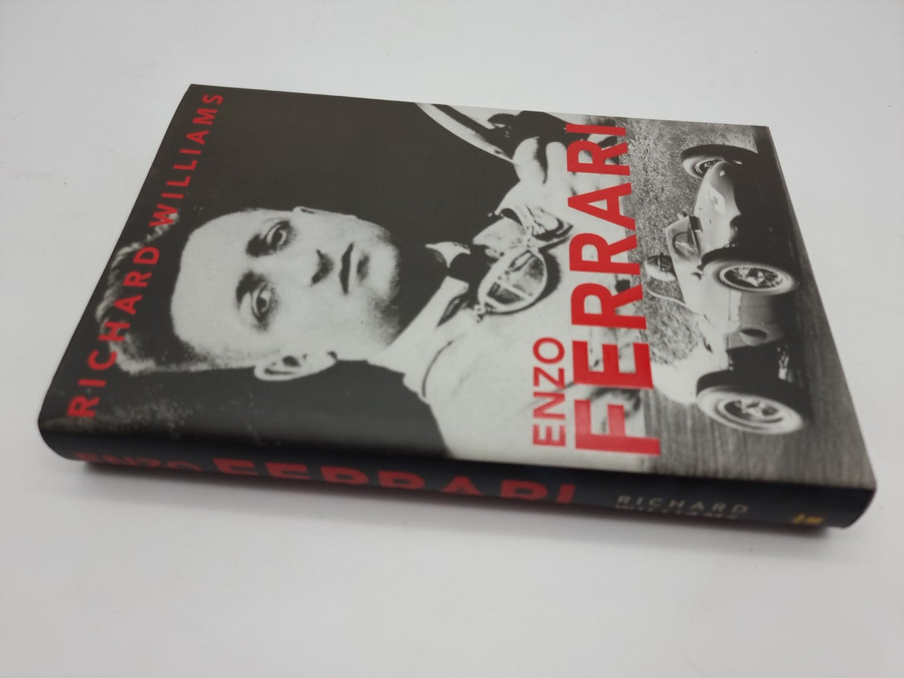 Hardcover book cover angled view with red title lettering and black-and-white portraits