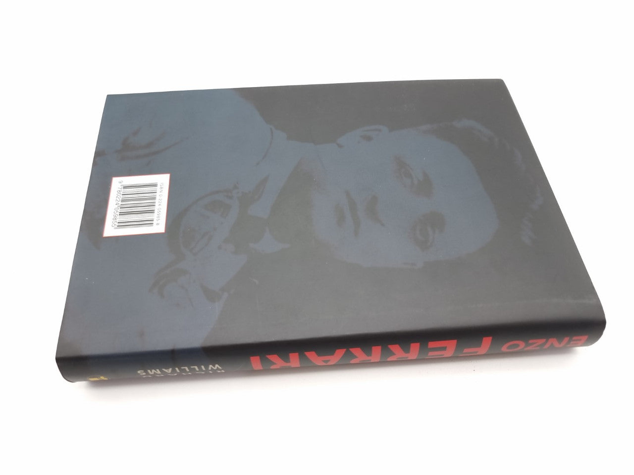 Hardcover book with dark cover, red title text, and black-and-white racing photo