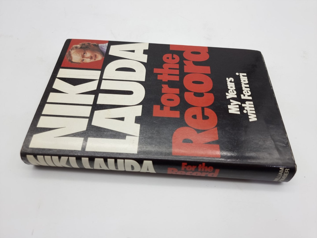 Closed hardcover motorsport memoir book with bold red and white cover typography.