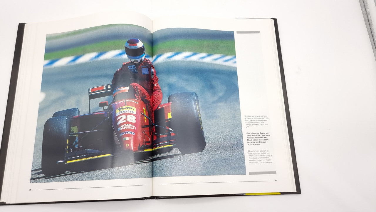 Photographic review book open to a color photo spread of a Formula 1 race car