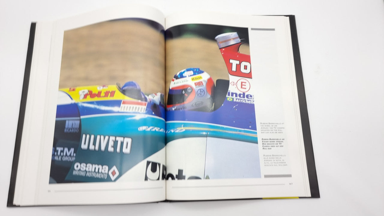 Photographic review book open to a color spread with a racing car and driver helmet
