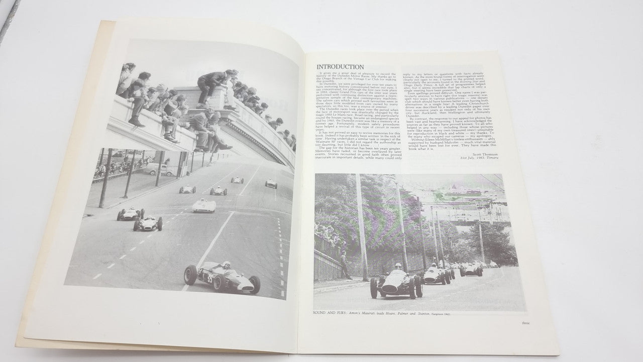 Open race-history book spread with black-and-white track photos and paragraphs