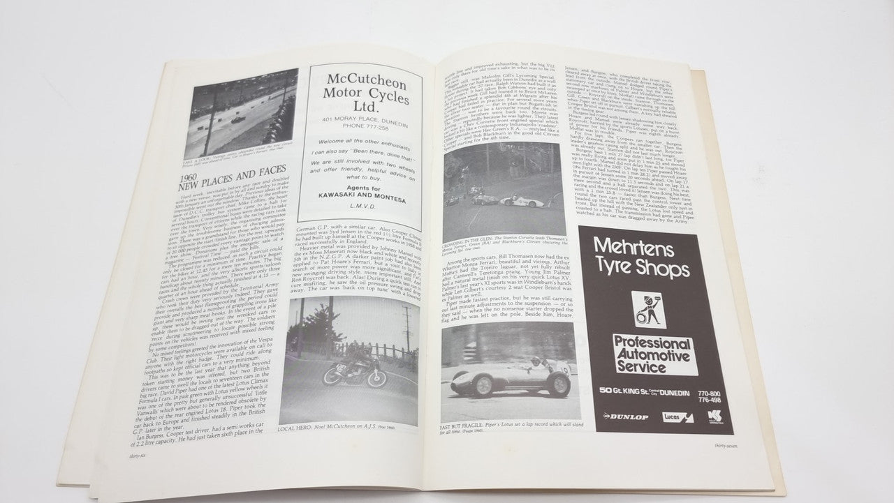 Open race-history book spread with two columns of text and car ads