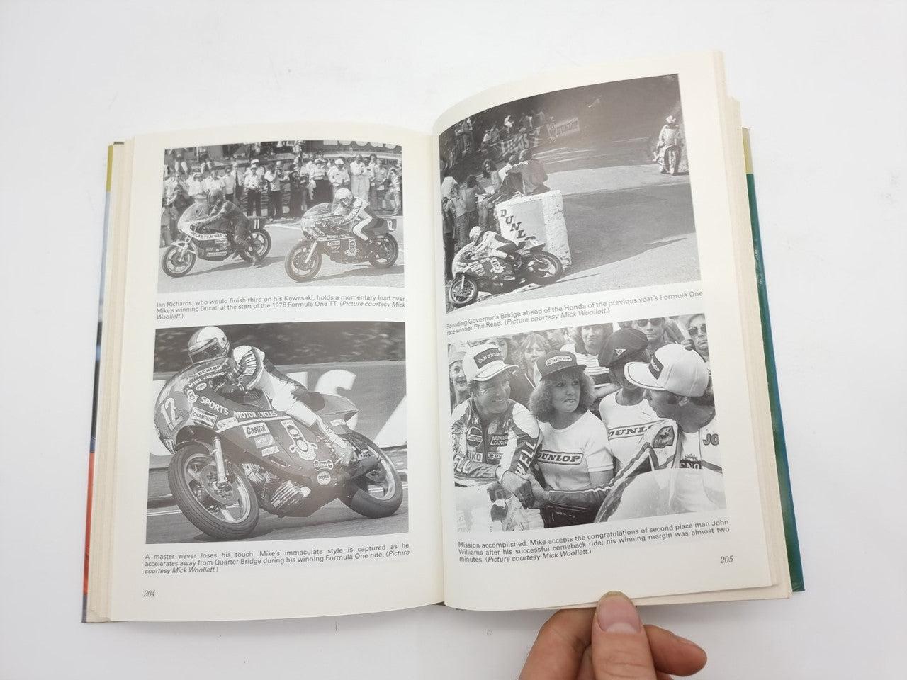 Book open showing black-and-white motorcycle racing photos across two pages