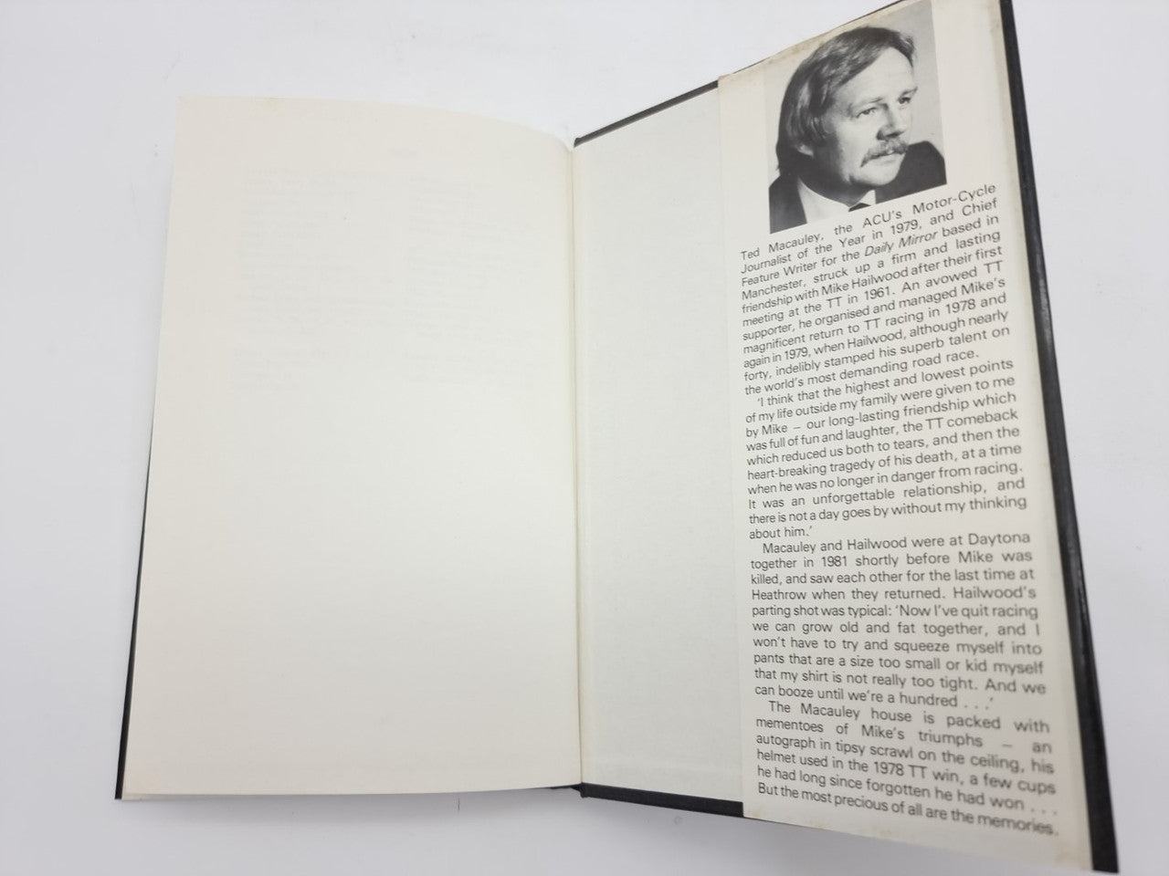 Book open with blank left page and biography-style text on the right.