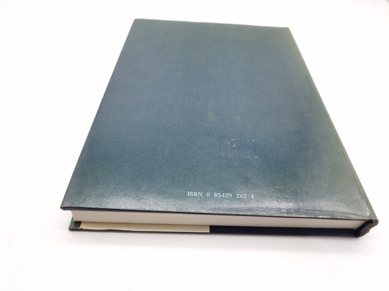 Hardcover book spine side with dark teal textured cover and small printed details.