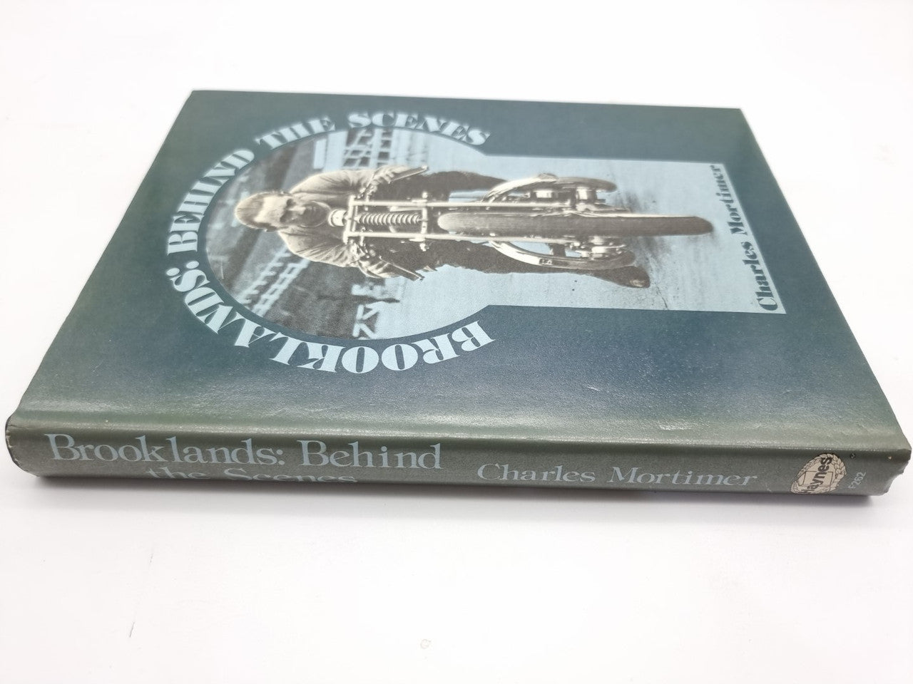 Hardcover book with dark teal cover and motorcyclist illustration plus title lettering.