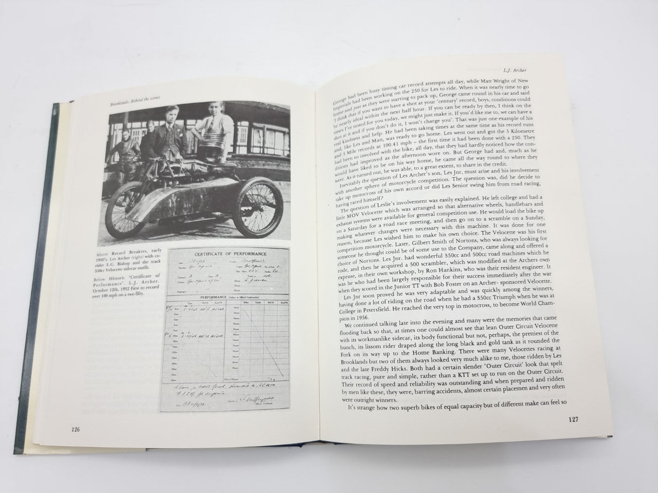 Open paperback book with printed text, black-and-white motorcycle photo, and charts