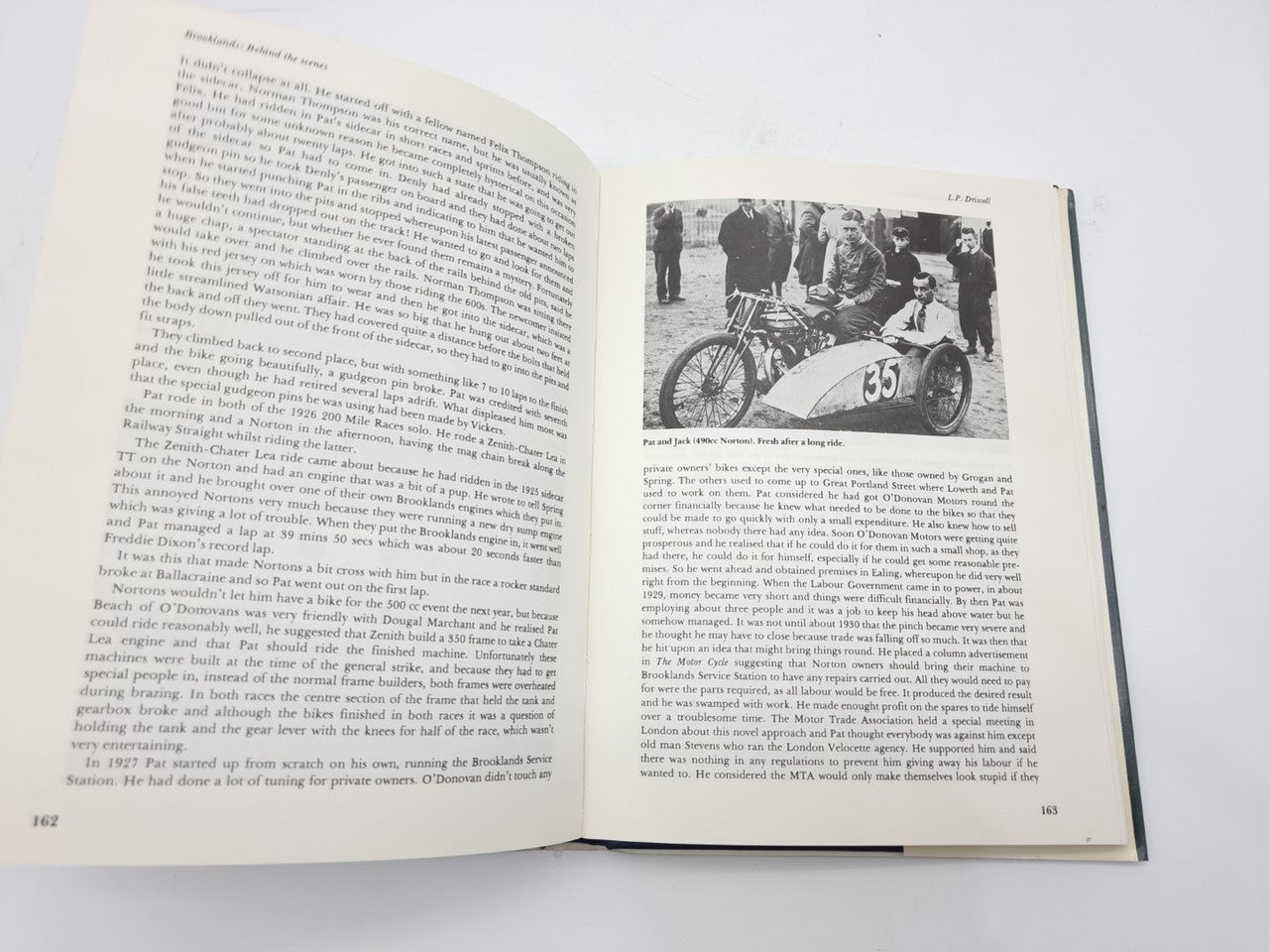 Open paperback book with printed text and black-and-white motorcycle race photo