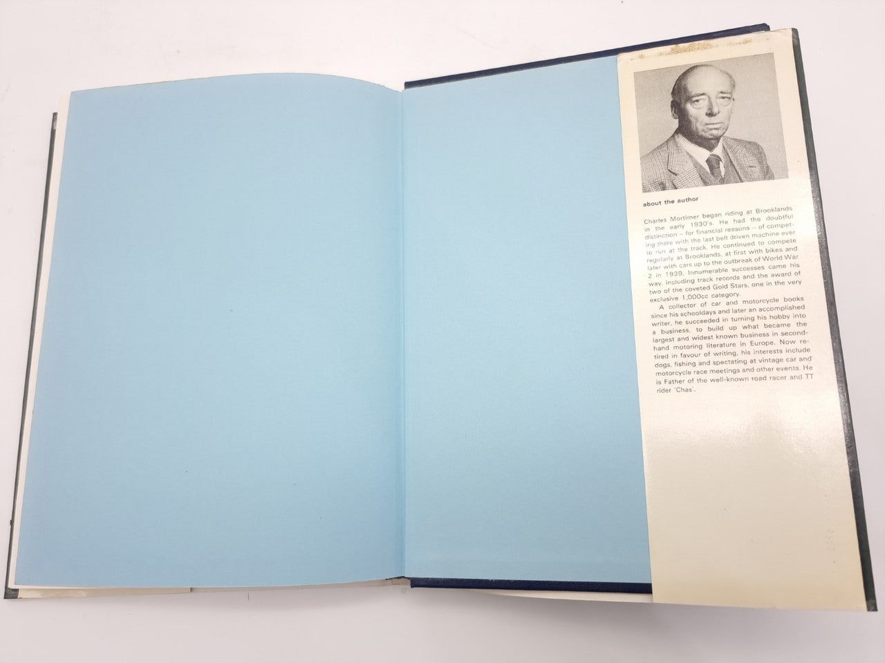 Open paperback book with blank blue pages and a page with portrait and text