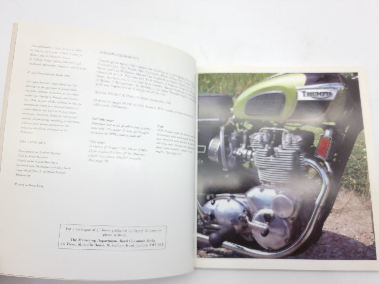 Open hardcover motorcycle photo book with text left page and green and silver bike photo right