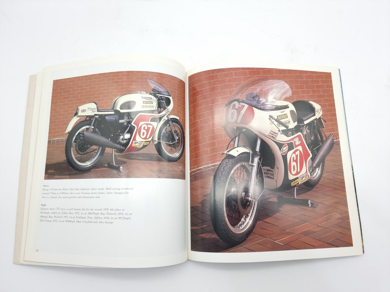 Open hardcover motorcycle photo book featuring a red and black motorcycle on two pages