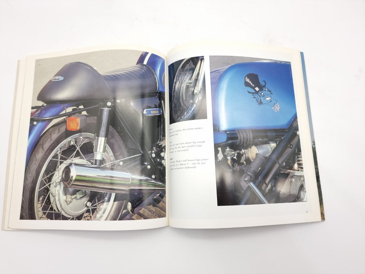 Open hardcover motorcycle photo book with blue and dark bike images across two pages