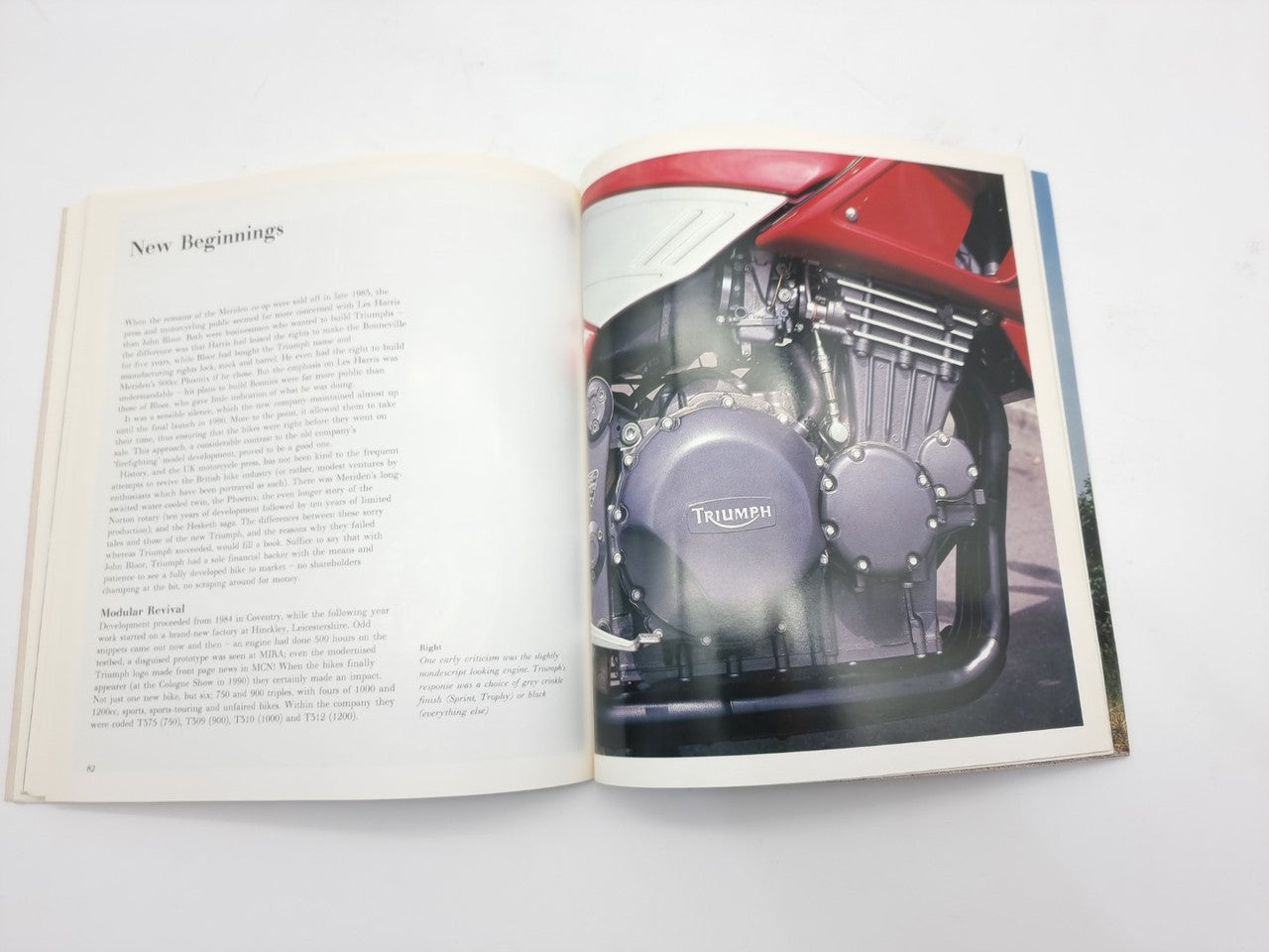 Open hardcover motorcycle photo book with an engine close-up on the right page