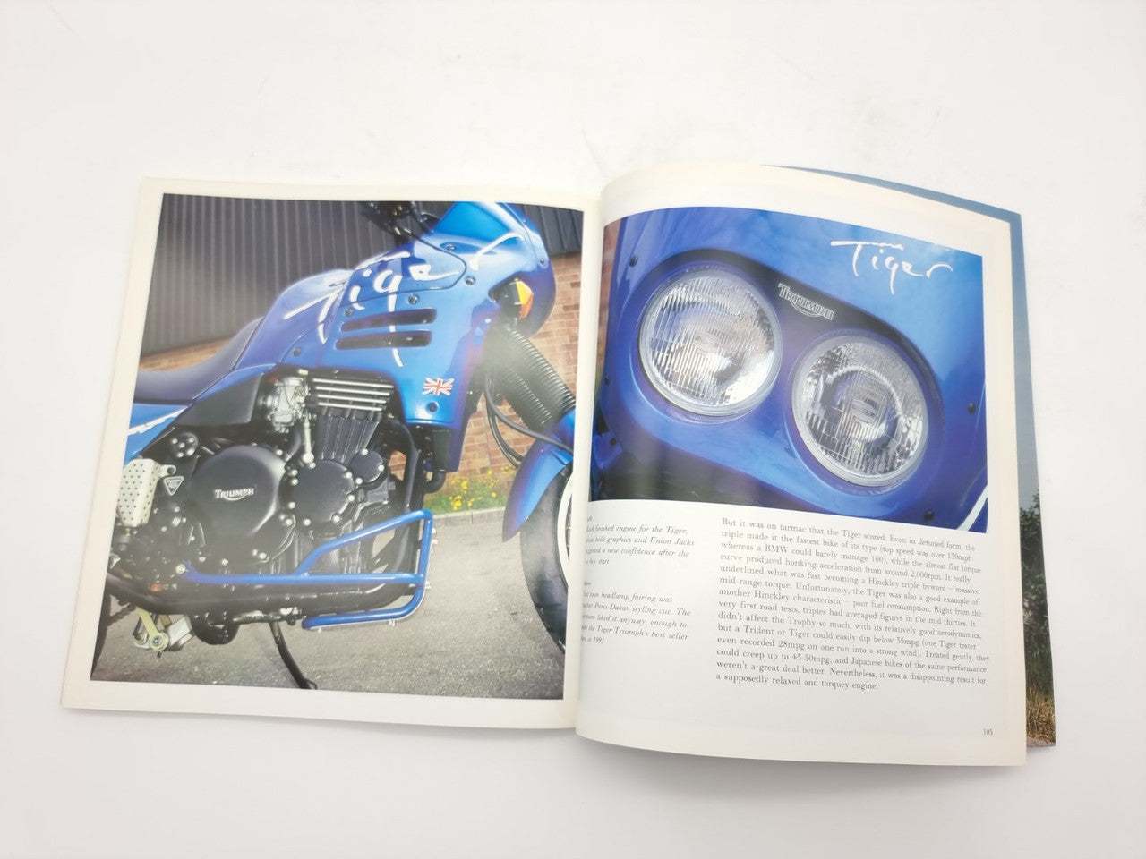 Open hardcover motorcycle photo book showing a blue motorcycle fairing and engine details
