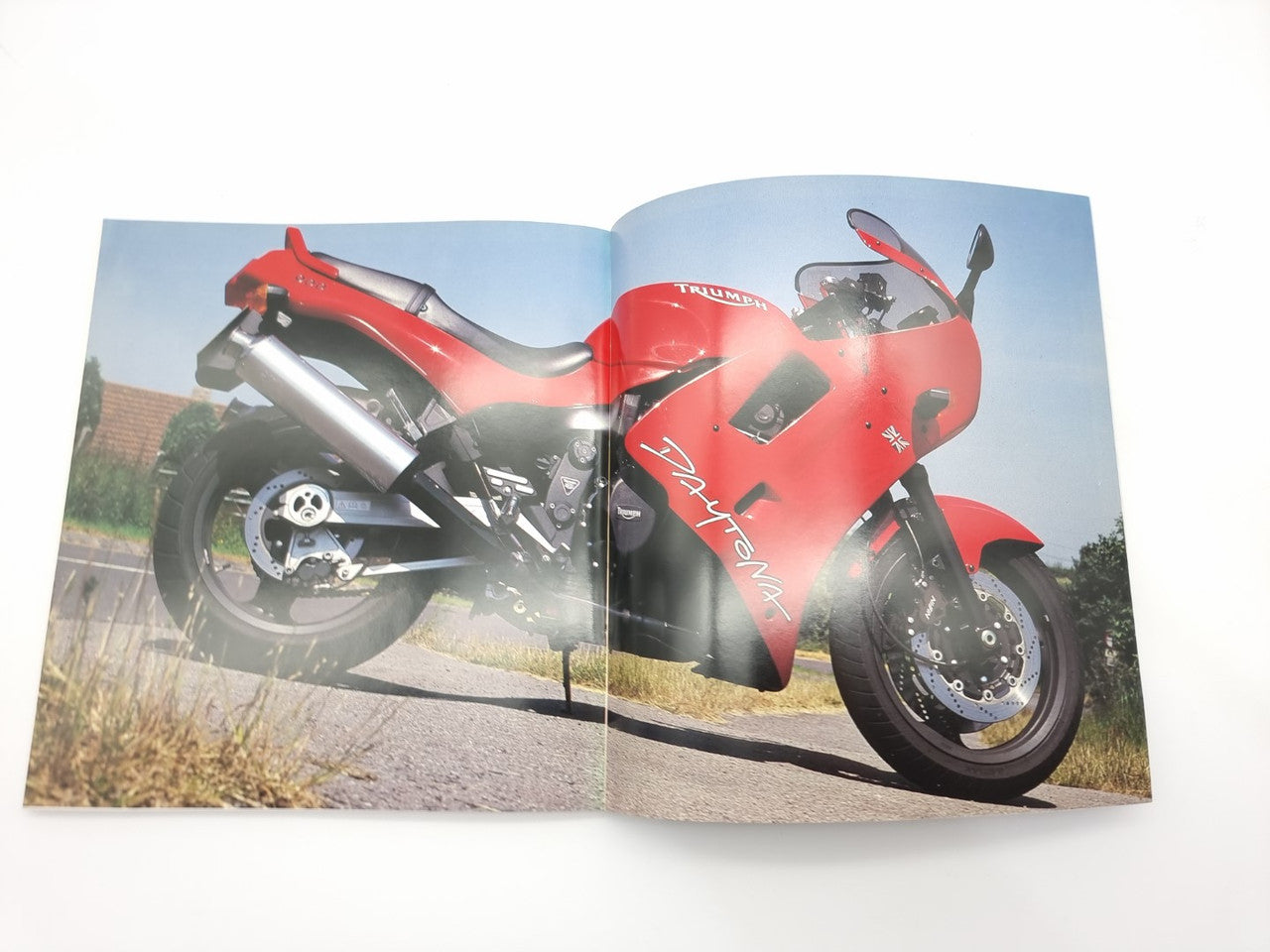 Open hardcover motorcycle photo book with a red sport bike on a road