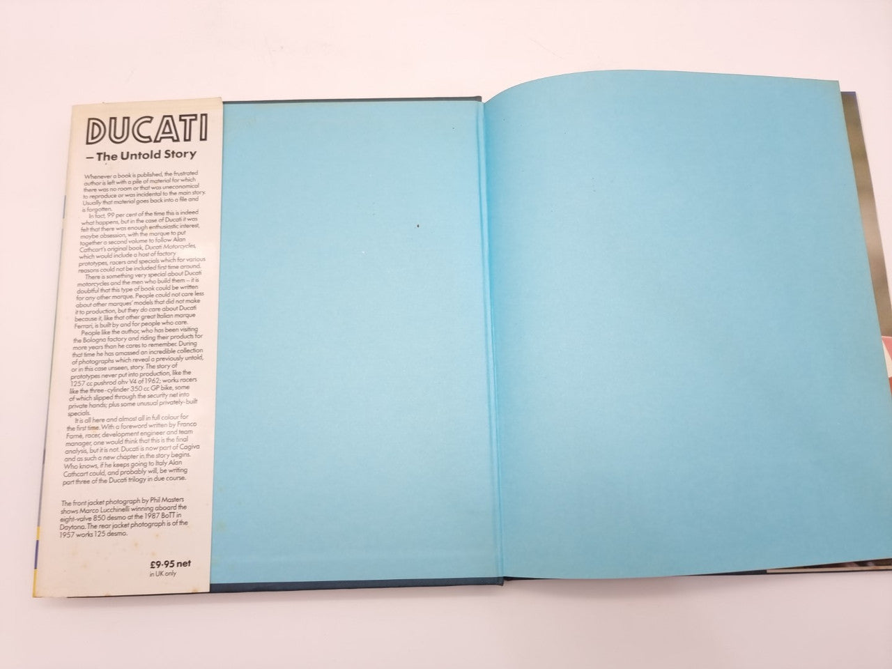 Open Ducati racing book with text on the left page and blank blue right page