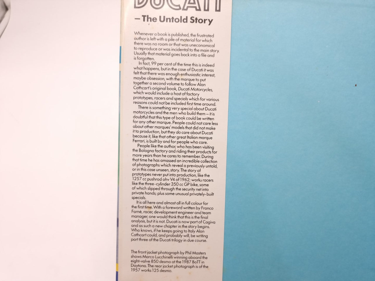 Open Ducati racing book page with dense printed text and yellow border
