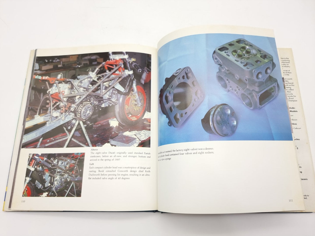 Open motorcycle history book with engine parts photos on right and chassis photos on left