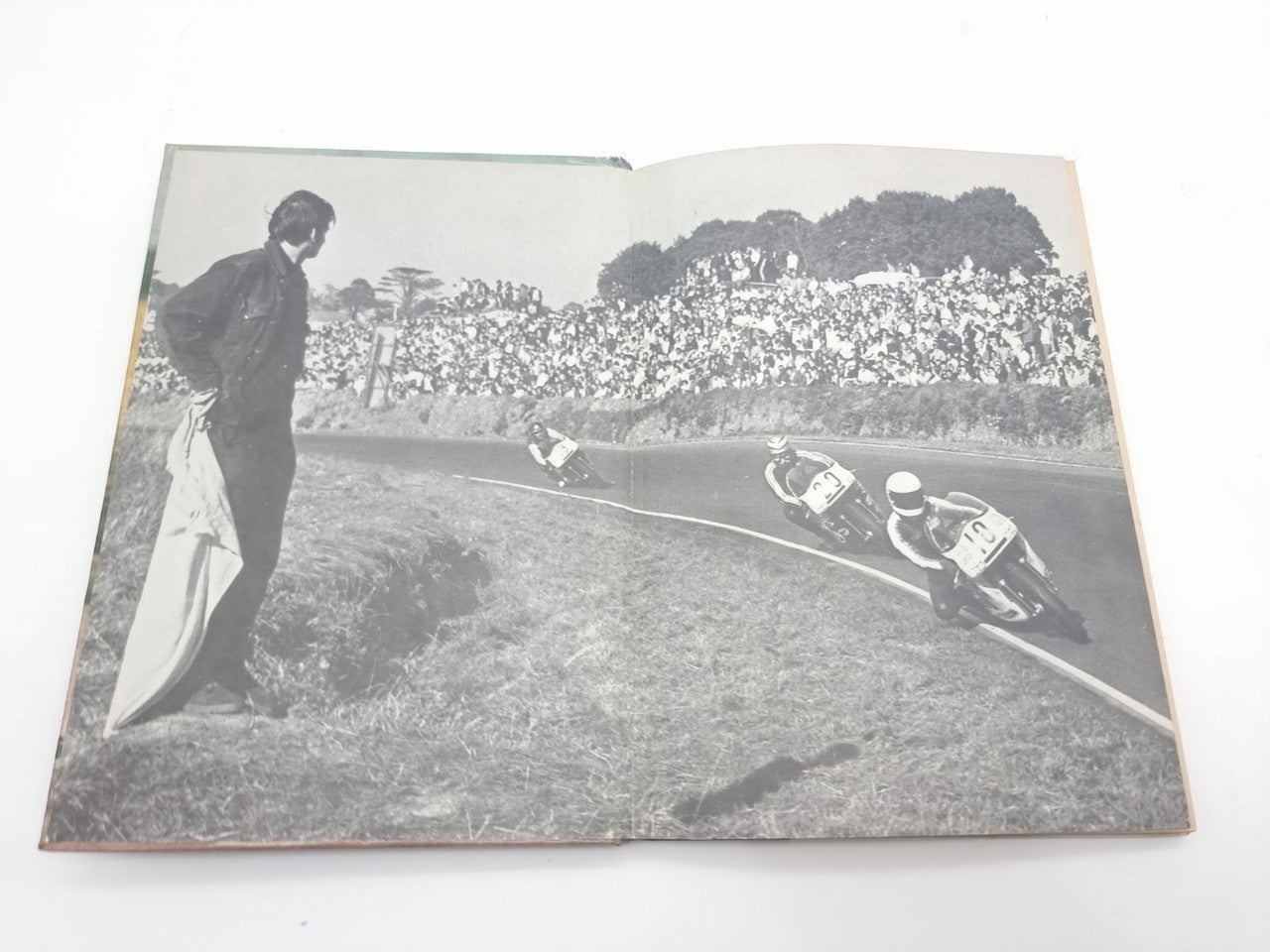 Motorcycle racing manual spread showing a black-and-white track photo with riders on a curve