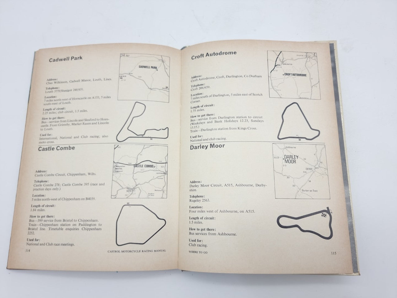 Motorcycle racing manual open to track maps with labeled circuit diagrams
