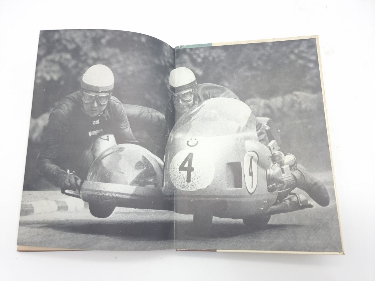 Motorcycle racing manual open to black-and-white photo of two racers on motorcycles