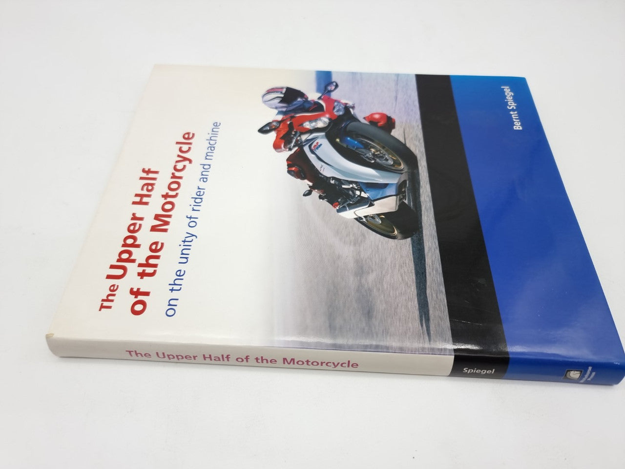 Hardcover book side view with motorcycle cover art and blue spine band