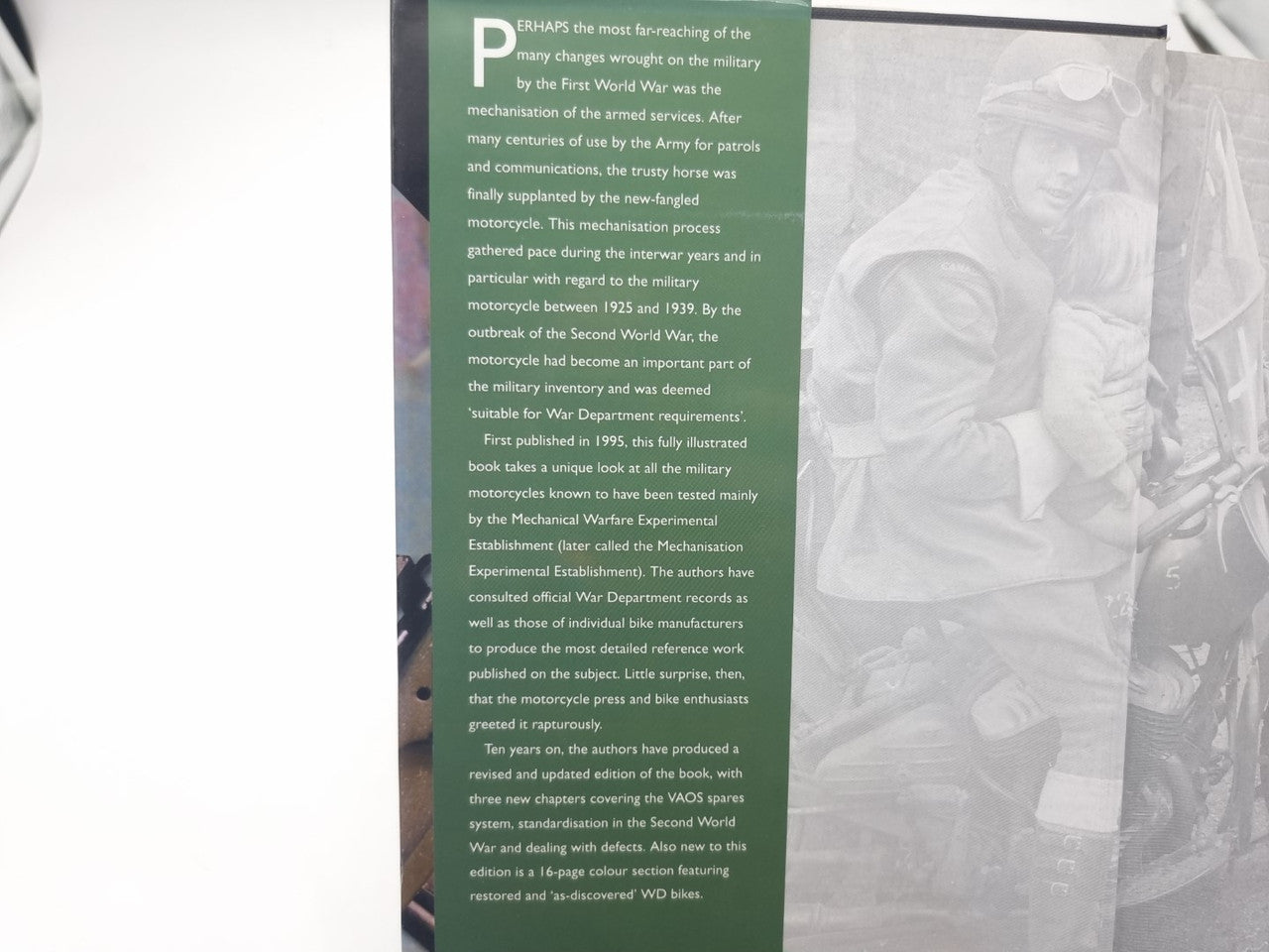 Hardcover book open to inside cover with green text panel and motorcycle portrait