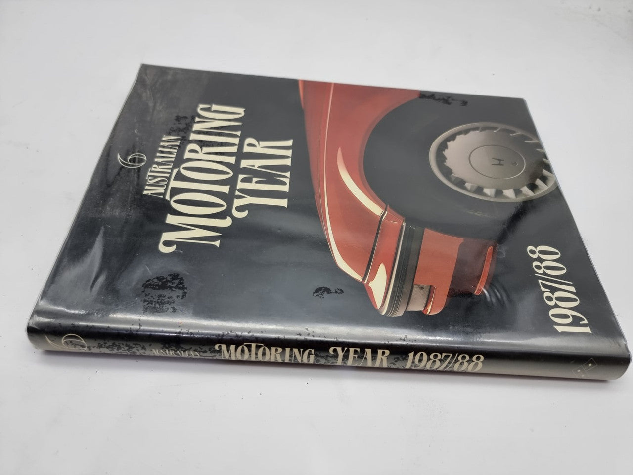 Motoring Year 1987/88 book cover, black with red car art and side wheel