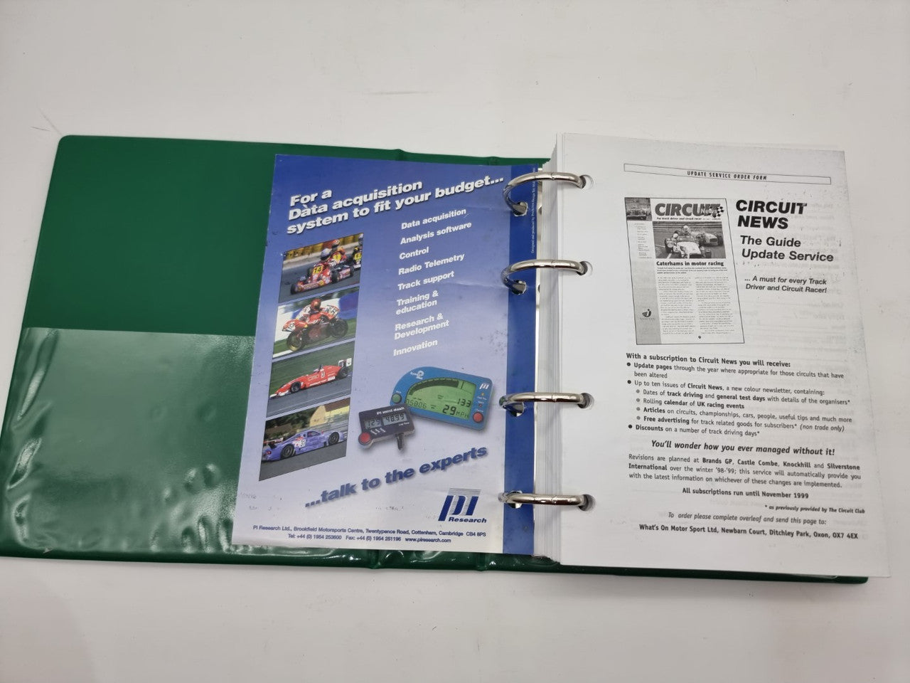 Open circuit guide binder showing printed pages with colorful racing images