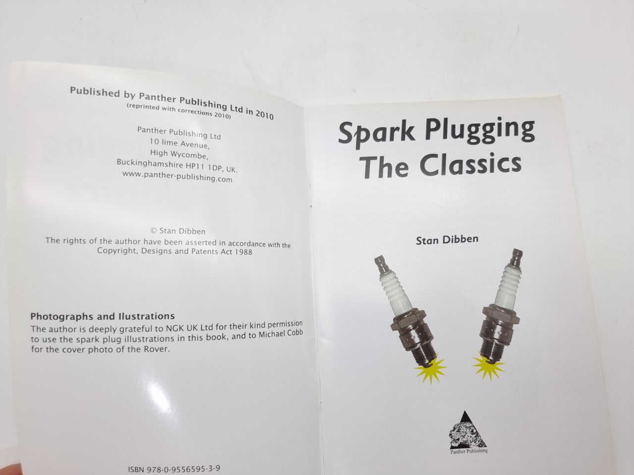 Paperback book pages with copyright text and cover art showing two spark plugs